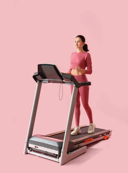 粉红背景的跑步机上漂亮女子训练 — 图库照片