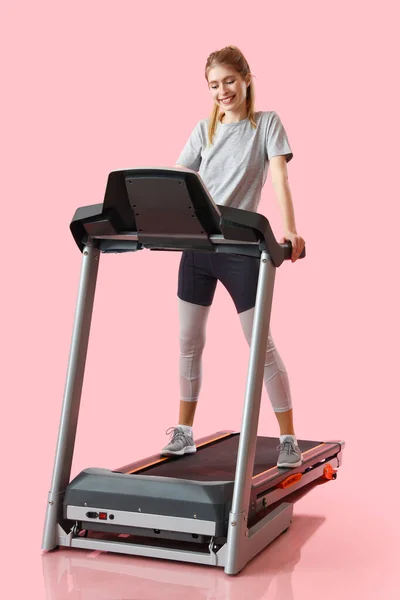 在粉红背景下的跑步机上训练的体态健壮的年轻女子 — 图库照片