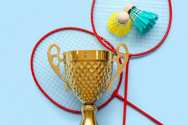 Goldpokal Mit Badmintonschlägern Und Federbällen Auf Blauem Hintergrund — Stockfoto