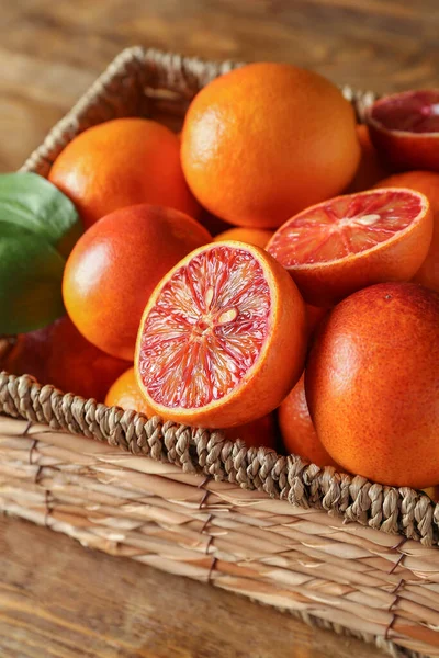 Wicker box with tasty blood oranges on wooden background