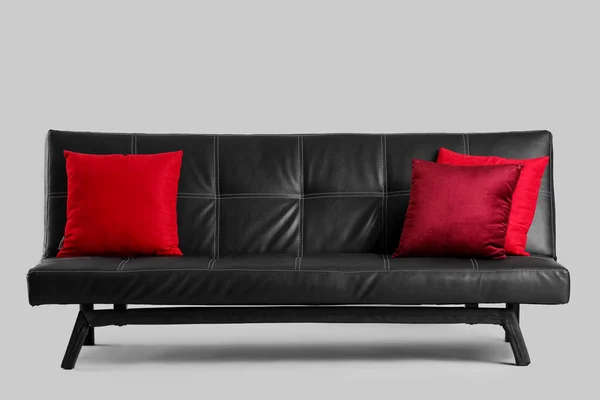 灰色背景上有红色衬垫的时髦黑色沙发 — 图库照片