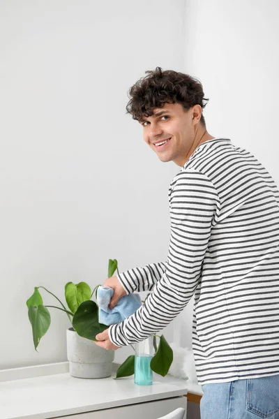 Mladý Muž Čistí Pokojovou Rostlinu Doma — Stock fotografie
