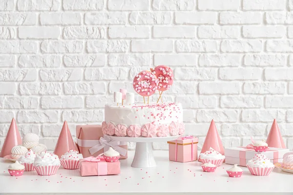 靠近砖墙的白色桌子上放糖的生日蛋糕 — 图库照片