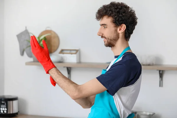 年轻人把橡胶手套放在厨房里 — 图库照片