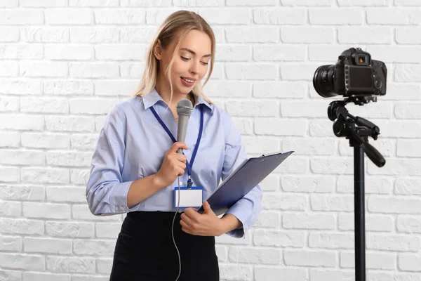 Female Journalist Microphone Clipboard Recording Video White Brick Background — Stock Photo, Image