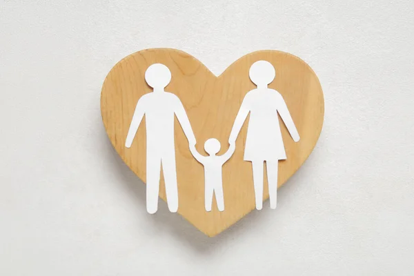 Wooden heart with figures of family on white background
