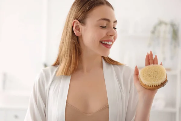 Young woman with anti-cellulite brush in bathroom, closeup