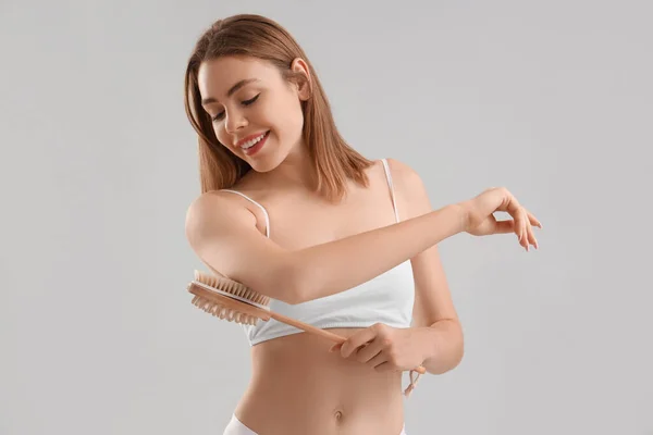 Jovem Mulher Massageando Seu Braço Com Escova Celulite Fundo Claro — Fotografia de Stock