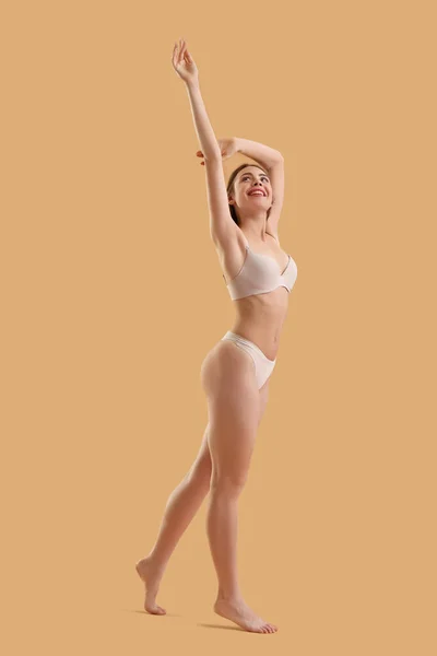 Young woman with cellulite problem on beige background