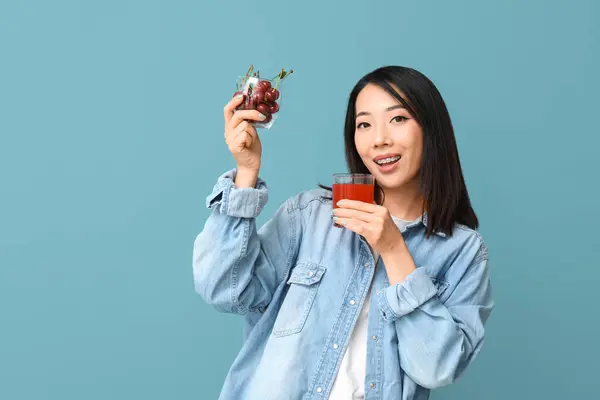 Schöne Asiatin Mit Kirschen Und Einem Glas Saft Auf Blauem — Stockfoto