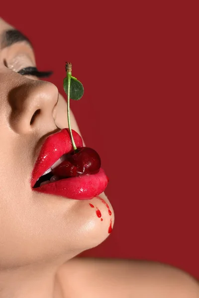 赤い背景でチェリーを食べる美しい女性 クローズアップ — ストック写真