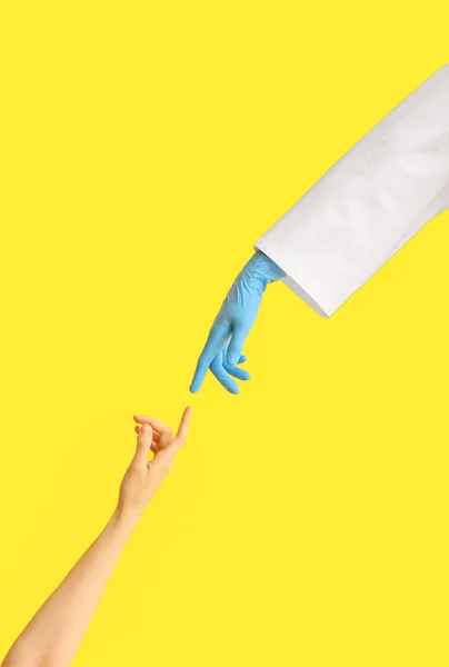 患者の手と医師の手が黄色の背景に達する — ストック写真