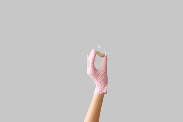 Kvinnlig Läkares Hand Med Hörapparat Grå Bakgrund — Stockfoto