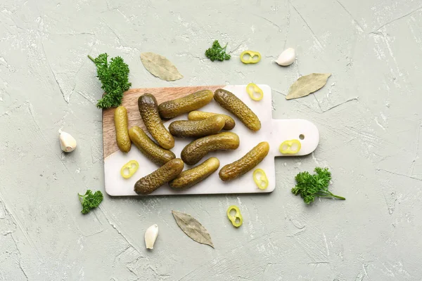 stock image Board with pickled cucumbers and different spices on grey background