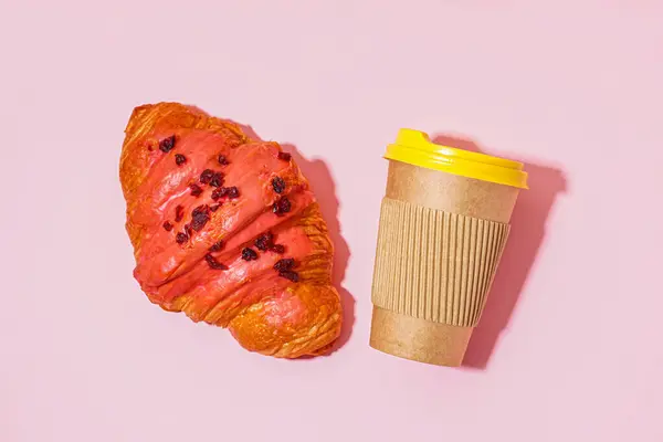 粉红桌上的甜羊角面包和纸杯咖啡 — 图库照片