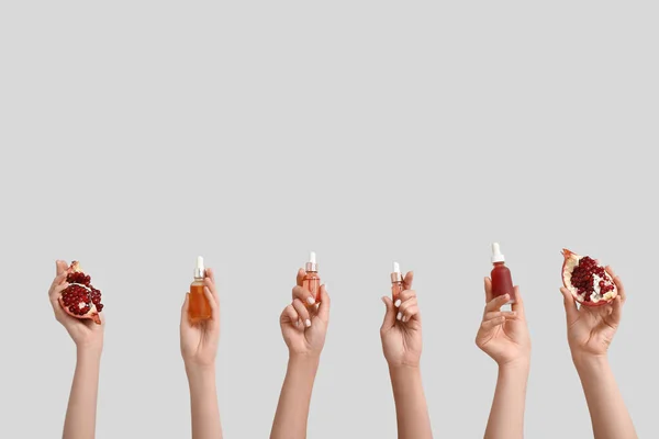 Female Hands Holding Bottles Cosmetic Products Pomegranate Grey Background — Stock Photo, Image