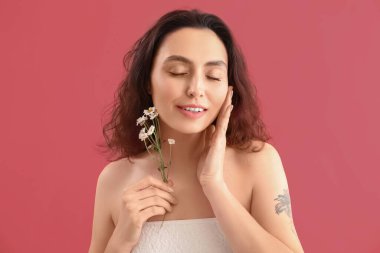 Pembe arka planda papatya çiçekleri olan genç esmer kadın, yakın plan