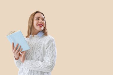 Bej arka plan üzerine kitap okuyan genç bir kadın.