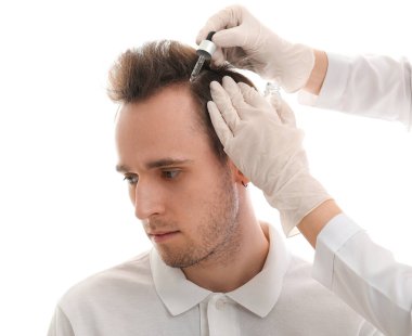 Genç adam beyaz arka planda saç büyümesi için serum alıyor, yakın plan.