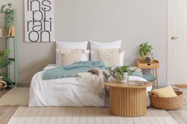 Yatak odasının içinde rahat bir yatak ve sehpanın üzerinde bitkiler var.