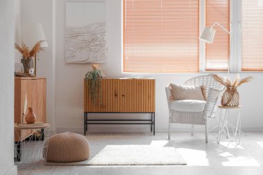 Parlak oturma odasının içinde rahat koltuklar ve ahşap dolaplar var.