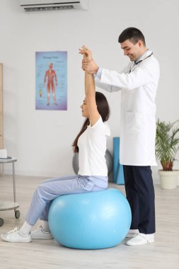 Erkek doktor klinikteki genç kadının duruşunu kontrol ediyor.