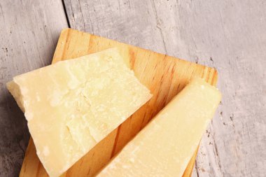 Hafif ahşap arka planda lezzetli parmesan peyniri parçaları olan tahta, yakın plan.