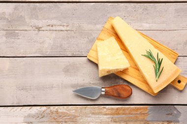 Hafif ahşap arka planda lezzetli parmesan peyniri parçaları olan tahta.