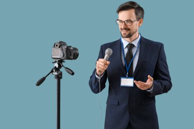 Mavi arka planda mikrofon kayıt videosu olan erkek gazeteci