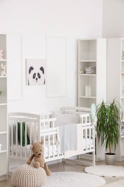 Bebek yatağı ve raf ünitesi olan beyaz tonlu çocuk odasının şık bir iç mekanı.