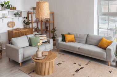 Kahve masasında gri kanepeler ve Gerbera çiçekleri olan aydınlık oturma odasının içinde.