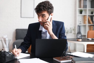 Masada defterle çalışan genç işadamı.