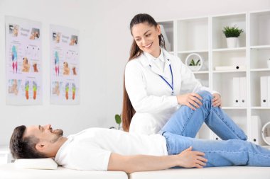 Rehabilitasyon merkezinde genç bir adamla çalışan kadın fizyoterapist.