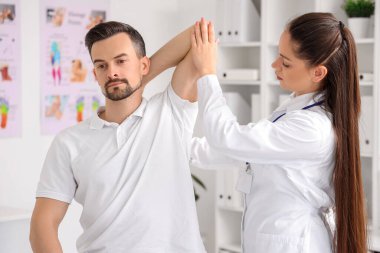 Rehabilitasyon merkezinde genç bir adamla çalışan kadın fizyoterapist.