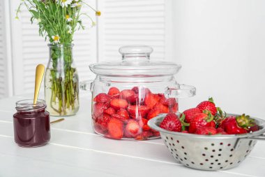 Tatlı çilek reçelli kavanoz ve mutfaktaki masada taze böğürtlen.