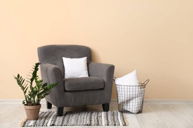 Beyaz yastıklı gri koltuk, bej duvarın yanında.