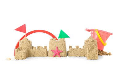 Beyaz arka planda kumsal oyuncakları ve bayrakları olan kumdan kale