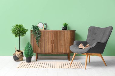 Interior of living room with grey armchair, wooden cabinet and striped rug