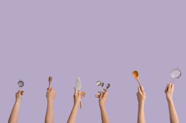 Leylak arka planında pişirme aletleri olan kadın eller.