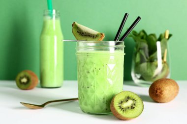 Bardak ve beyaz masada naneli taze kivili smoothie.