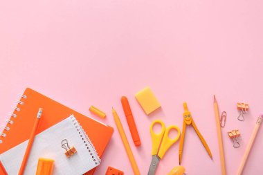 Pembe arka planda farklı okul kırtasiyesi ve defter