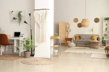 Gri kanepesi, kahve masası ve çiçekleri olan aydınlık oturma odasının içinde.