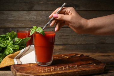 Ahşap arka planda lezzetli domates suyu içen bir kadın.