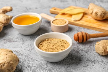 Taze zencefil kökleri, kase ve ahşap kaşık. Mavi arka planda kurutulmuş toz.