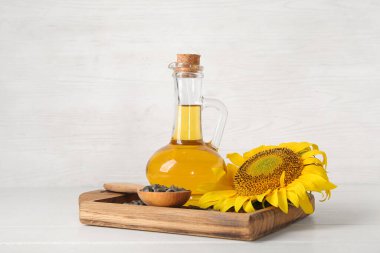 Beyaz ahşap arka planda tohumları olan ayçiçeği yağı ve tahtasının dekanı