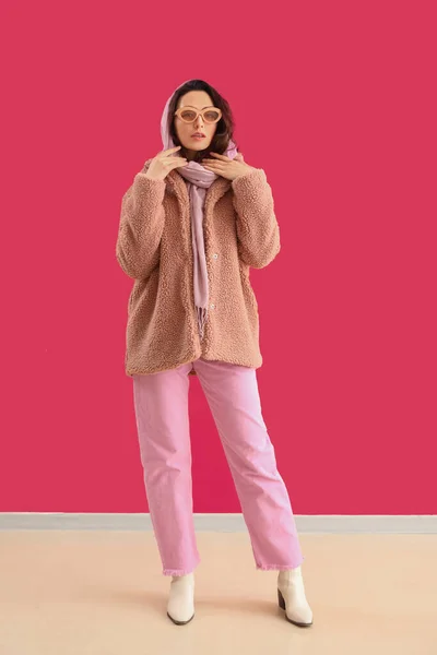 粉红墙壁附近穿着泰迪熊外套和太阳镜的时髦年轻女子 — 图库照片
