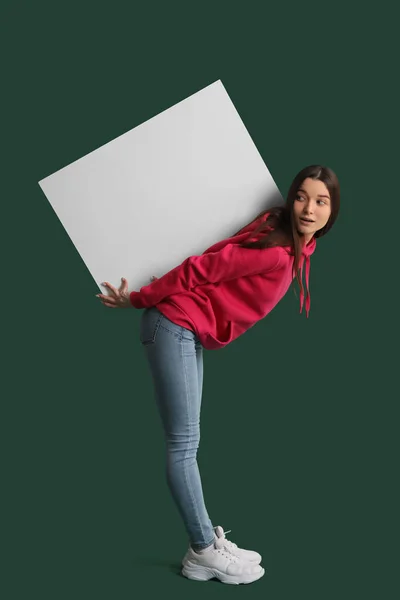 若いです女性でパーカーで大きなブランクポスターで緑の背景 — ストック写真