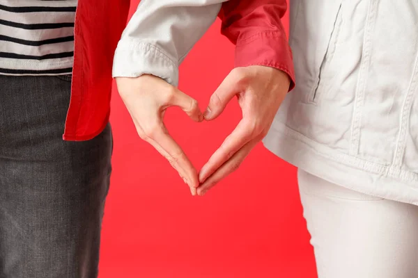 赤い背景に手でハートを作る若いカップル クローズアップ — ストック写真