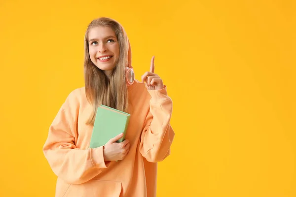 Junge Frau Mit Buch Zeigt Auf Etwas Auf Gelbem Hintergrund — Stockfoto