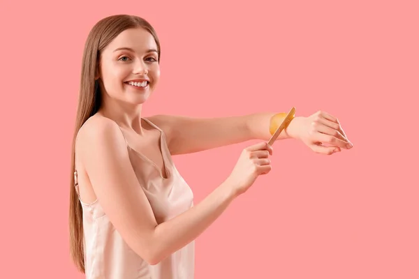 Ung Kvinna Tillämpa Socker Pasta Hennes Arm Mot Rosa Bakgrund — Stockfoto
